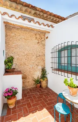 a patio with a table and chairs and a brick wall at Apartamento rústico reformado con encanto (Garraf) in Sant Pere de Ribes