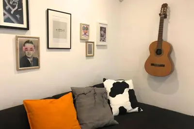 a living room with a couch and a guitar on the wall at M5 Cool Terrace. Metro 1 min. Center 15' by metro in Esplugues de Llobregat