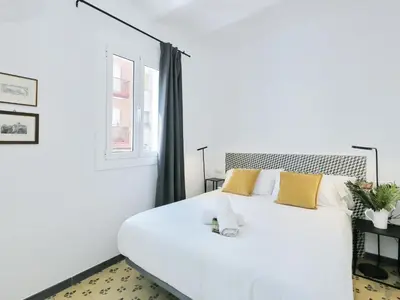 a white bedroom with a large white bed with yellow pillows at Casa nanit apt d in Hospitalet de Llobregat