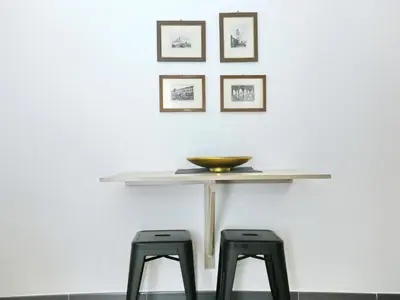a table with two stools in front of a white wall at Casa nanit apt d in Hospitalet de Llobregat