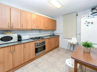 a kitchen with wooden cabinets and a table and a refrigerator at Apartment Camp Nou by Interhome in Barcelona
