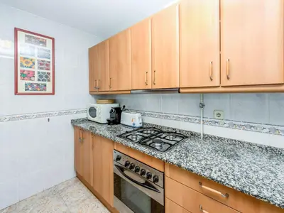 a kitchen with wooden cabinets and a stove top oven at Apartment Camp Nou by Interhome in Barcelona