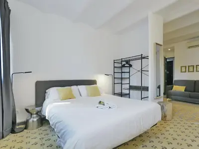 a bedroom with a large white bed and a couch at Casa nanit apt b in Hospitalet de Llobregat