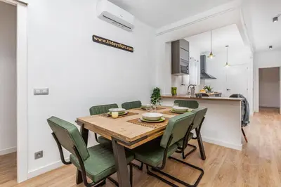 a dining room with a wooden table and green chairs at Poble Sec 3BR 2BA Balcony Sleeps 7 in Barcelona