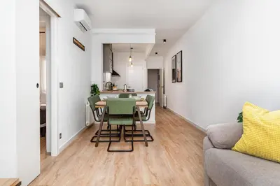 a living room with a table and chairs and a kitchen at Poble Sec 3BR 2BA Balcony Sleeps 7 in Barcelona