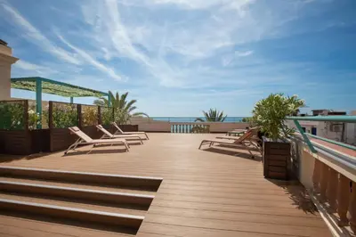 a deck with chairs and a view of the ocean at 1840 Apartments Sitges by Suma Hotels in Sitges