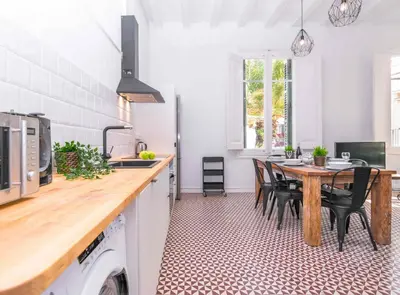 a kitchen with a wooden table and chairs in a kitchen at 1840 Apartments Sitges by Suma Hotels in Sitges