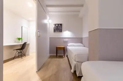 a small room with two beds and a desk at Mirador 1840 in Barcelona