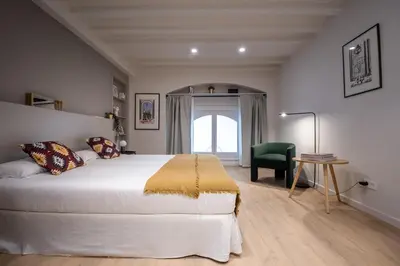 a bedroom with a large white bed and a green chair at Mirador 1840 in Barcelona