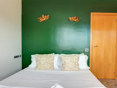 a bedroom with a white bed with a green wall at Los Condes Penthouse by Hello Homes Sitges in Sitges