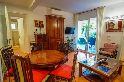 a living room with a wooden table and a dining room at Beach Apartment Garden Vinyet by Hello Homes Sitges in Sitges