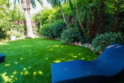 a blue bench in a yard with green grass at Beach Apartment Garden Vinyet by Hello Homes Sitges in Sitges
