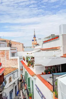 a view of roofs of buildings with a clock tower in the background at Velero Attic by Hello Homes Sitges in Sitges