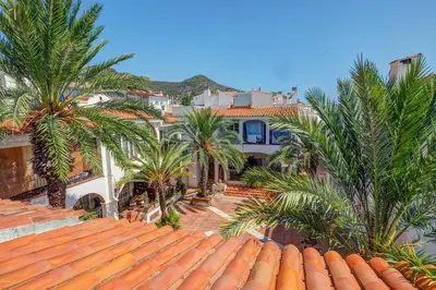 a large house with palm trees in front of it at Harbour terraces by Hello Homes Sitges in Sitges