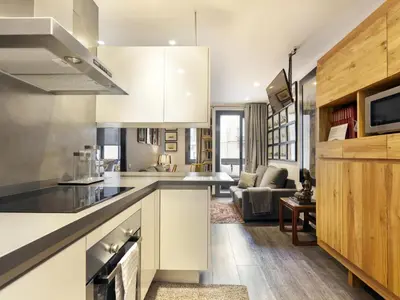a kitchen with white cabinets and a living room at Click&Flat Luxury cabanyes in Barcelona