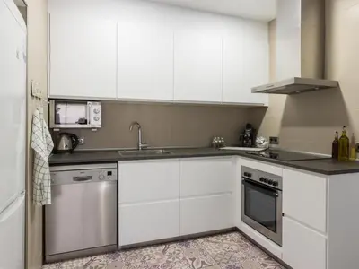 a kitchen with white cabinets and a sink and a dishwasher at Click&Flat Xoriguer in Barcelona