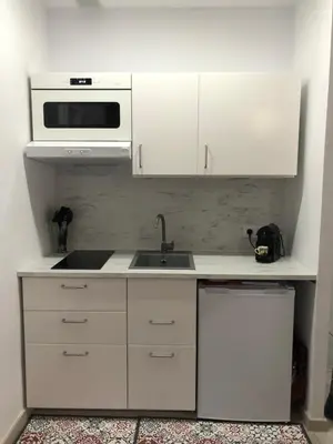 a white kitchen with a sink and a microwave at Àtico lumineux à 10 min du centre ville in Hospitalet de Llobregat