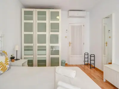a white bedroom with a white couch and glass cabinets at Sebastian Terrace Apartment by Hello Homes Sitges in Sitges