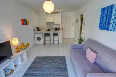 a living room with a blue couch and a kitchen at White Penthouse by Hello Homes Sitges in Sitges