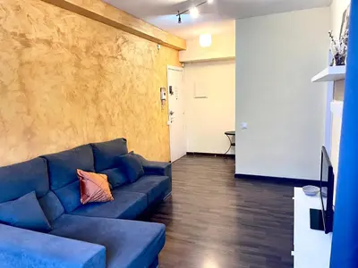 a living room with a blue couch and a hallway at APARTAMENTO BARCELONA in Barcelona