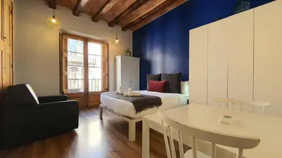 a bedroom with a bed and a table and a chair at Barrio Gotico Apartments Ferran in Barcelona