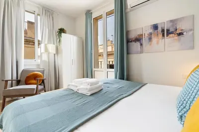 a bedroom with a bed and a chair and windows at Lodging Apartments Barceloneta Beach Studio 42 in Barcelona
