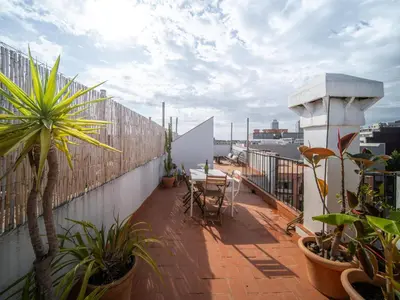 a balcony with tables and plants on a building at White penthouse in Barcelona