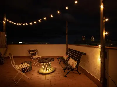 a patio with a table and chairs and lights at White penthouse in Barcelona