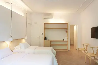 a white room with two beds and a television at The MO House in Barcelona