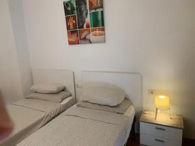 two beds in a room with a lamp on a table at APARTAMENTO construcción nueva BARCELONA - CALELLA in Calella