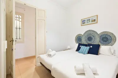 a white bedroom with a large white bed with blue pillows at Stay U-nique Apartments Mistral in Barcelona
