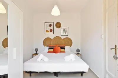 a white bedroom with a large white bed with orange pillows at Stay U-nique Apartments Mistral in Barcelona