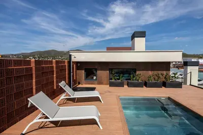 a patio with two chairs and a swimming pool on a roof at Art Apartments BCN in Castelldefels