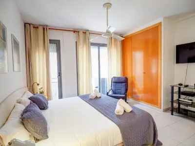a bedroom with a large bed with a blue chair at Apartamento Burdeos by Hello Homes Sitges in Sitges