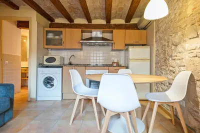 a kitchen with a wooden table and white chairs at Alcam Santa Monica in Barcelona