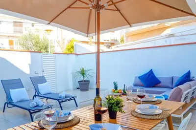 a patio with a table and chairs and an umbrella at Sebastian Patio by Hello Homes Sitges in Sitges