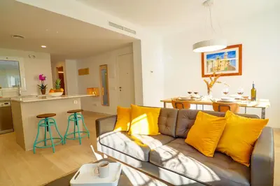 a living room with a couch and a kitchen at Sebastian Patio by Hello Homes Sitges in Sitges