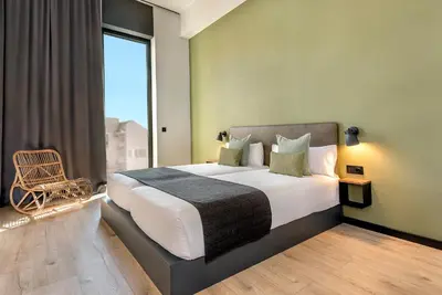 a bedroom with a large bed with a large window at Hotel Orangine in Hospitalet de Llobregat