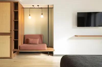 a bedroom with a pink chair and a tv at Hotel Orangine in Hospitalet de Llobregat