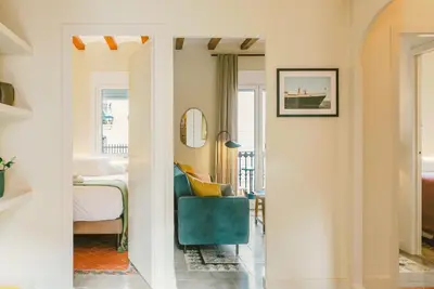 a living room with a green chair and a bedroom at Brummell Apartments Montjuic in Barcelona