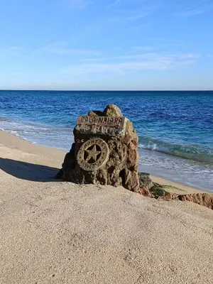 a rock sign on a beach with the ocean at Casa grande y céntrica con piscina en zona peatonal in Montgat
