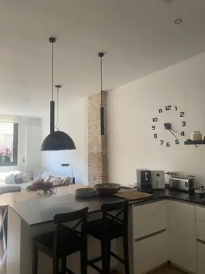 a kitchen with a table and chairs and a clock on the wall at Casa grande y céntrica con piscina en zona peatonal in Montgat