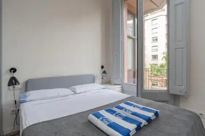 a white bed with a blue and white towel on it at ApartEasy - Casanova Elegance in Barcelona