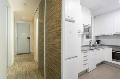 a kitchen with white cabinets and a wooden wall at ApartEasy - Casanova Elegance in Barcelona