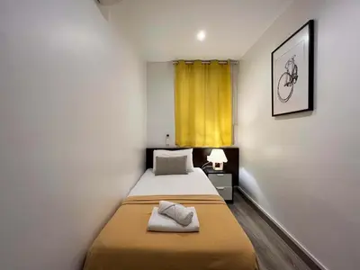 a small room with two beds and a yellow curtain at Stay U-nique Apartments Tordera in Barcelona