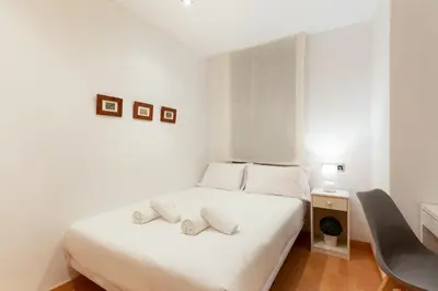 a white bedroom with a bed with towels on it at Stay U-nique Apartments Terrassa in Barcelona