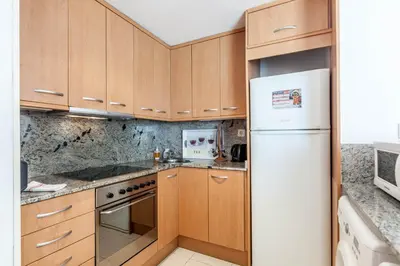 a kitchen with wooden cabinets and a white refrigerator at Stay U-nique Apartments Industria in Barcelona