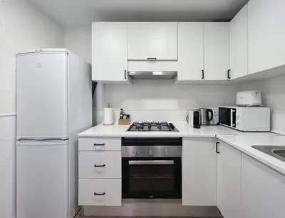 a white kitchen with white cabinets and a refrigerator at Stay U-nique Apartments Rocafort in Barcelona