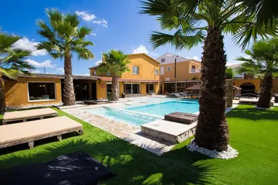 a swimming pool with palm trees in front of a house at Catalunya Casas Relax and Recharge - only 34km from Barcelona! in Rubí