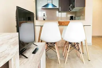 a kitchen with two white chairs and a television at Mazi Apartments Terrace in Mataró